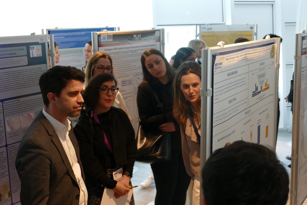 Group of colleagues at a poster session examining scientific posters displayed on boards in a bright conference room.