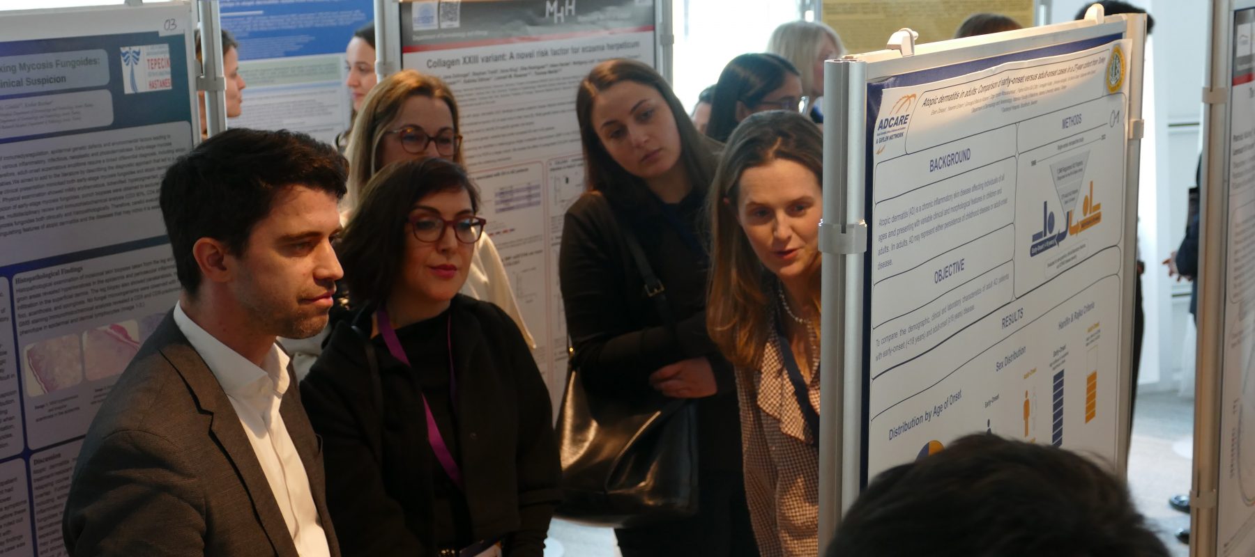 Group of colleagues at a poster session examining scientific posters displayed on boards in a bright conference room.